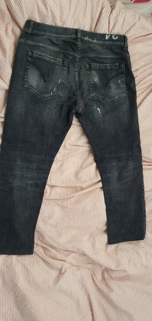 Mökrgråa Dondup jeans med slitningar - Säljer nu dessa mörkgråa Dondup jeans med sjukt snygga slitningar. Säljes för dem aldrig kommer till användning. Modellen på jeansen hetee George och är ifrån grunden skinny fit. Men jag som har två andra par Dondup George skulle säga att dem sitter som slim fit. Tveka inte på att ställa frågor om du har några funderingar! Skulle säga att dem passar folk som är runt 171-176 hållet och väger drygt 68-71 kg. Storleken 34 motsvarar ungefär W31/W32 L30