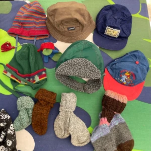 Barn mössor, kepsar stl 50-52 och raggsockor - Flera olika huvudbonader: randig stickad mössa i rött och grönt med tofs, grön mössa Sätila Elite med mönster och knytband, brun bucket hat från Dubster, blå keps från Toys factory, blå och röd keps med tryck Winnies summer, samt grön vintermössa med grått foder och knäppning. Perfekt för barn som vill ha variation!