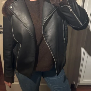 Svart skinnjacka - Säljer denna svarta skinnjacka från H&M i storlek XS. Jackan har klassisk bikerstil med bred krage, silverfärgade dragkedjor och detaljerade fickor. Använd fåtal gånger🪩