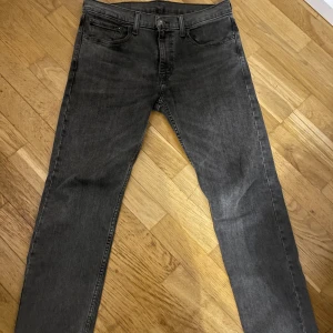 Levi's 502 grå jeans W32 L32 - Snygga grå jeans från Levi's modell 502 med klassisk femficksdesign och raka ben. Jeansen har en mörkgrå tvätt och är tillverkade i slitstarkt bomullsmaterial. Passar dig som gillar en stilren och enkel look med lite edge.