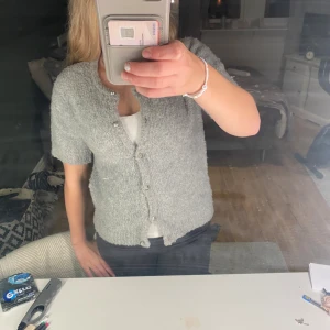 Grå kofta med pärlknappar Gina Tricot - Supermysig grå kofta från Gina Tricot i storlek XS. Koftan har korta ärmar, rund hals och är gjord i ett fluffigt stickat material. Stängs med silvriga pärlknappar framtill och har en loose passform som ger en chill vibe.l