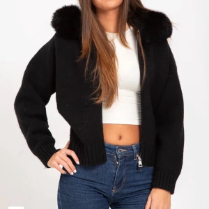 Svart cardigan jacka med päls ( Alessa) - Svart cardigan jacka med fluffig päls runt luvan och grov ribbad mudd vid ärmslut och nederkant. Jackan är croppad och har lång ärm, perfekt för att ge en chill men ändå stylish vibe. Materialet är stickat och pälsen ger extra edge till looken. Den är lite noppriga vid armarna annars inget. Kan skicka mera bilder om de behövs. Original pris är ca 2000. Den är också hyfsat varm. Pris kan diskuteras 