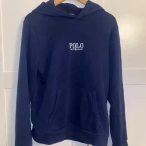 Mörkblå Ralph Lauren hoodie - Säljer en stilren mörkblå ralph lauren hoodie. Storlek XL i junior som motsvarar XS, passar ungefär 166-176. Nypris ca 1100kr. Tröjan är i ett bra skick utan fläckar elr slitage. Kommer från en rök- och djurfritt hem. Hör av dig vid frågor elr likande🙌