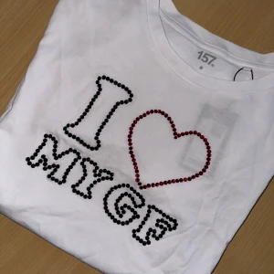 T-shirt - I ❤️ my gf  - Säljer en vit t-shirt från 157 i storlek M med texten 'I ❤️ MY GF' framtill. Bokstäverna är dekorerade med svarta och röda pärlor som ger en cool och unik look. Tröjorna går att tvätta OBS! Bara i 30 grader, ingen torktumling 
