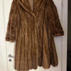Brun pälsjacka i mink - Säljer en brun pälsjacka med bred krage och snyggt fall. Jackan har ett lyxigt, fluffigt utseende. Perfekt för dig som vill sticka ut och hålla dig varm under kalla dagar. Märkt med BL på insidan.