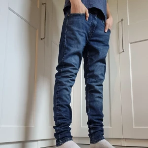 Levi's 511 blå jeans W30 - Snygga blå Levi's 511 jeans i slim fit med klassisk femficksdesign och knappgylf. Jeansen har en smal passform och är tillverkade i mjukt jeanstyg som sitter skönt. Perfekt för dig som gillar en modern och stilren look. Modellen är 171 cm 