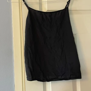 Svart linnetopp från H&M XS - Svart linnetopp från H&M i storlek XS. Tunn och slät med smala axelband och rak passform. Materialet är mjukt och lätt, perfekt för varma dagar. Enkel och stilren design utan mönster eller detaljer. Snygg att matcha med jeans eller kjol.