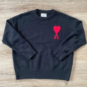 Ami Paris tröja - Svart stickad tröja från Ami med rund hals och ribbade muddar. På bröstet finns ett rött hjärta med bokstaven A, som är typiskt för märket. Storlek S passform slim fit. Skriv vid eventuella frågor. Pris kan diskuteras.
