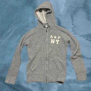 Grå hoodie från Abercrombie & Fitch - Säljer min sjuktttt feta Abercrombie tröja i stl L.  Den är perfekt nu till kallare dagar när man vill vara varm. Den har inga hål eller andra fel vilket är varför priset är som det är. Dock vid en snabb affär kan prsiet sänkas en aning ☺️.