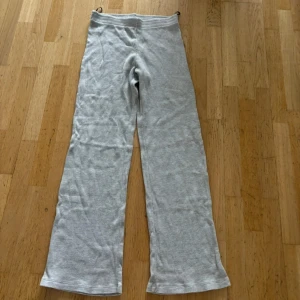 Grå mjukisbyxor med wide fit - Superbekväma grå mjukisbyxor med breda ben och elastisk midja. Perfekta för chill dagar hemma eller när du vill ha en avslappnad stil. Materialet är mjukt och stretchigt för extra komfort.