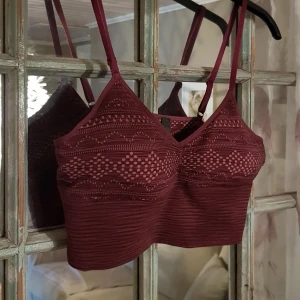 Vinröd linnetopp från Bodyzone KappAhl - Säljer en vinröd linnetopp från Bodyzone KappAhl i storlek M. Toppen har smala axelband, v-ringad hals och ett snyggt mönster med meshdetaljer och geometriska former. Materialet är mjukt och stretchigt, perfekt för en chill och trendig look.