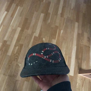 Svart Gucci keps med ormtryck - Säljer en svart keps från Gucci med GG-monogram och en röd och vit orm på framsidan. Digitalt kvitto i mitt namn finns, pris kan diskuteras!! Helst snabb affär. Storlek: M