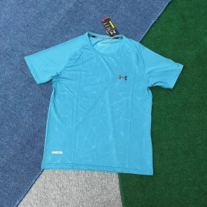 Blå träningst-shirt från Under Armour - Snygg blå t-shirt från Under Armour med diskret mönster och logga på bröstet. Perfekt för träning med sitt lätta och svala polyestermaterial. Klassisk passform och korta ärmar gör den både bekväm och stilren.