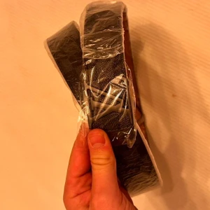 L v svart rutigt skärp - Snyggt  bälte med klassiskt rutigt mönster i svart och mörkgrått. Bältet har en silverfärgad som spänne och insidan är i beige skinn med präglad märkning. Perfekt accessoar för att lyfta din outfit.