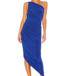 Blå Diana Gown från Norma Kamali - Supersnygg långklänning från Norma Kamali i intensivt blått. One-shoulder design med draperad effekt och asymmetrisk nederkant som ger en cool och elegant siluett. Tillverkad i stretchigt material som sitter tajt och framhäver figuren. Aldrig använd. Lappar kvar. Nypris 2900 sek 