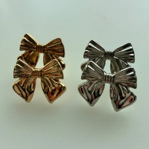 Smyckesset med två par örhängen och armband  - Säljer ett smyckeset med två öppna armband i guld, ett slätt samt ett tvinnat och två par rosettformade örhängen i både guld och silver. Armbanden kommer från hm, örhängena från Ur och Penn!