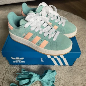 Adidas Campus mintgrön/rosa 36⅔ - Helt nya och oanvända Adidas Campus sneakers i mintgrön mocka med klassiska rosa ränder och vit sula. Skorna har rund tå, platt gummisula och vita snören. Extra mintgröna skosnören medföljer. Perfekt för dig som vill sticka ut med färg och stil. Även kartongen medföljer!🩵🩷
