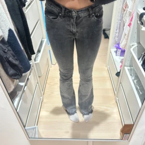 Svarta bootcut jeans med slitna kanter - Snygga svarta jeans med bootcut passform och slitna kanter längst ner. Jeansen har klassisk femficksdesign, knapp och dragkedja framtill samt en mörk tvätt som ger en cool vibe. Perfekta för dig som gillar en avslappnad men trendig stil.