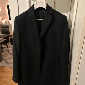 Svart kavaj från J.Lindeberg, stl 48 - Säljer min Svarta J.Lindberg rock för den kommer inte till användning och hänger bara i garderoben.. snygg o stilig helt i nyskick skickar även med galgen. Nypris 4000kr 2024.
