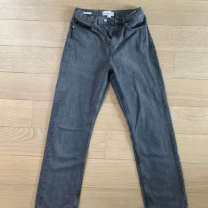 Grå high rise jeans från Calvin Klein - Snygga grå jeans från Calvin Klein Jeans med high rise och straight fit. Klassisk femficksmodell med logga på bakfickan och metallknapp framtill. Perfekta för dig som gillar en stilren och tidlös look.