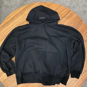 Essentials fear of god black hoodie  - Svart Fear of God Essentials hoodie i mycket bra skick. Klassisk och stilren modell med perfekt passform och skönt material. Använd varsamt och väl omhändertagen. Hör gärna av dig om du undrar något eller vill ha fler bilder.