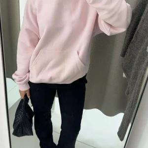 Ljusrosa hoodie med huva - Säljer en ljusrosa hoodie med huva och stor magficka. Tröjan har en loose passform och är långärmad, perfekt för chill dagar. Mjuk och skön, tillverkad i bomullsmix. Enkel design utan mönster eller logga.