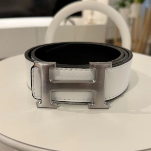 Vitt bälte med grått spänne  - Ett riktigt snyggt vitt bälte med topp kvalité för rimligt pris. Det gråa spänner matchar om perfekt med den vita färgen och skapar den unika looken.
