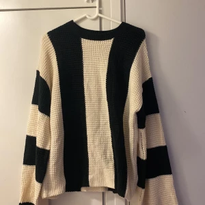 Svartvit randig stickad tröja - Säljer en grovstickad tröja med breda svarta och vita ränder. Tröjan har långärmade ärmar och en rund halsringning. Materialet är tjockt och mjukt, perfekt för kyliga dagar. Passformen är loose och ger en avslappnad vibe.