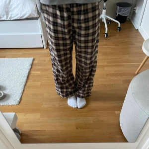 Bruna pyjamasbyxor  - Säljer ett par bruna och beige rutiga byxor från H&M i storlek 152. Byxorna har en loose passform och är tillverkade i mjukt bomullstyg. Perfekta för en chill och avslappnad stil med breda ben och elastisk midja. Så fina och säljer på grund av att jag har vuxit ur dem💕🌸
