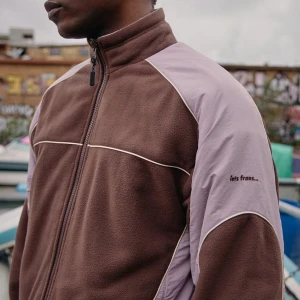 Reversibel Fleecejacka från Iets Frans i brunt och lila - Få två-i-ett-stil med denna vändbara jacka från Iets Frans… Den har ena sidan i enkel fleece och den andra sidan i paneler av fleece och ripstop, toppad med piping. Designad med hel dragkedja vid kragen, sänkta axlar, framdragkedja, långa ärmar, elastiska ärmslut, tre fickor och elastisk nederkant. Endast hos UO. Helt ny och oanvänd, köpt från UO:s webbplats. Var för stor i storlek för mig eftersom den har en ganska boxig passform.