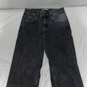 Svarta raka jeans med rå kant - Snygga svarta jeans med rak passform och rå, fransad kant vid benslut. Klassisk femficksmodell med knapp och dragkedja framtill. Jeansen har en mörk tvätt och är tillverkade i slitstarkt denimtyg. Perfekta för dig som gillar en enkel men cool stil.