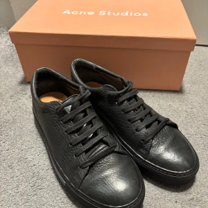  Acne Studios - Skor från Acne Studios, modellen heter Adrian Grain. Svart skinn. Storlek 40.  Väldigt bra skick. Två skoppåsar och låda i original.