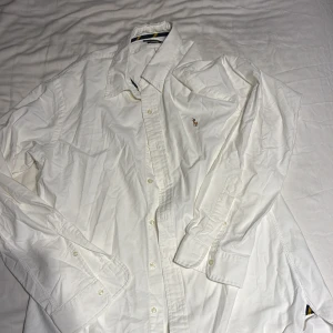 Vit skjorta Polo Ralph Lauren XL - Vit skjorta från Polo Ralph Lauren i slim fit-modell. Klassisk design med knappar framtill, lång ärm och broderad logga på bröstet. Tillverkad i mjuk bomull och passar perfekt för en clean och stilren look. ANVÄND 2 gånger