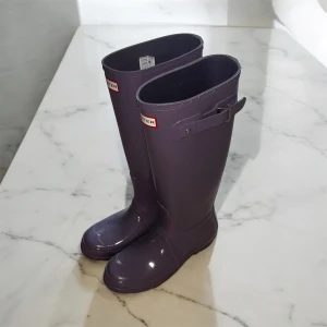 Lila Hunter stövlar  - Säljer ett par klassiska lila Hunter stövlar i glansigt gummi. Stövlarna har justerbart spänne på sidan och rund tå. Perfekta för regniga dagar och festivaler. Hunter-logga framtill och mönstrad sula för extra grepp.              ‼️Aldrig använda ‼️