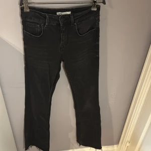 Svarta jeans med råa kanter från Zara - Svarta jeans från Zara med snyggt slitna, råa kanter nertill. Modellen har klassisk femficksdesign och svarta knappar. Jeansen har en passform som är tightare upp till och rak/flared nedtill och är tillverkade i ett stretchigt bomullsmaterial för extra komfort. Låg midja, precis vad som är inne nu. Använd 1 gång. Nypris: 399kr
