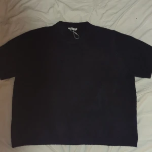 Mörkblå stickad tröja i oversize - En riktigt chill mörkblå stickad tröja i oversize-modell. Tröjan har korta ärmar och en enkel, rak passform som ger en avslappnad vibe. Perfekt för lager-på-lager och funkar året runt när du vill ha det bekvämt.