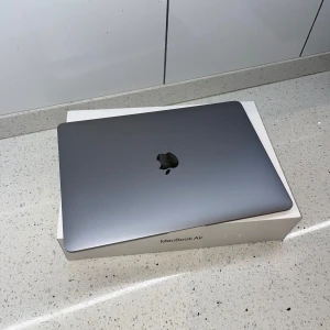 MacBook Air - Snygg MacBook Air i Space Gray med originalkartong. Datorn ser ut att vara i mycket gott skick utan synliga repor eller skador. Perfekt för studier, arbete eller vardagsbruk. Tunn, lätt och kraftfull med Apples välkända kvalitet.