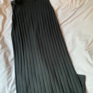 Svart ribbad långklänning från SHEIN - Svart långklänning från SHEIN i storlek M, MEN den är insydd så skulle säga att den är närmare storlek S nu. Klänningen är ribbad med vertikala ränder och har en enkel, stilren design. Materialet är mjukt och stretchigt, vilket gör den bekväm att bära. Perfekt för dig som gillar minimalistisk stil.