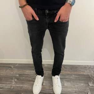 Svarta slim jeans Tiger of Sweden - Svarta jeans från Tiger of Sweden i slim fit-modell. Jeansen har klassisk femficksdesign, snygg tvättad finish och svart läderpatch i midjan. Tillverkade i Italien och perfekta för dig som gillar en smalare passform.