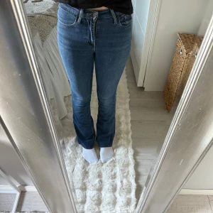 Levi's 725 High Rise Bootcut Jeans - Säljer ett par Levi's 725 High Rise Bootcut jeans i klassisk blå denim. Jeansen har hög midja, bootcut-ben och femficksdesign. Perfekt passform som framhäver figuren och ger en snygg siluett. Ikonisk Levi's-lapp bak och slitstarkt jeanstyg. Dem är nästan mer midrise än highrise.