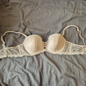 Beige spets bandeau från Esmara - Säljer en beige bandeau-tubtopp från Esmara med vacker spets och vadderade kupor. Axelbanden är flätade och avtagbara, vilket gör toppen perfekt för axelbandslösa looks. Spetsdetaljerna ger en romantisk vibe och materialet är mjukt mot huden.