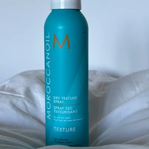 Moroccanoil Dry Texture Spray - Säljer en Moroccanoil Dry Texture Spray i en snygg turkos flaska med vitt lock och orange detaljer. Perfekt för att ge håret extra volym och textur. Passar alla hårtyper. Enkel att använda för en effortless look. 205 ML
