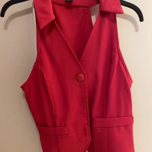 Mörkrosa väst med knappar från SHEIN  - Snygg mörkrosa väst med klassisk krage och tre  knappar framtill. Västen har två dekorativa fickor och är figursydd för en stilren look. Perfekt att styla över en skjorta eller t-shirt för en trendig outfit.