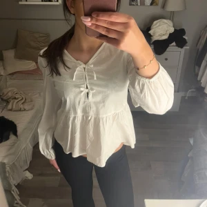 Vit blus  - Säljer en söt vit blus från Gina Young med knyt framtill och volang nertill. Blusen har långärmade puffärmar. Super gullig verkligen💘