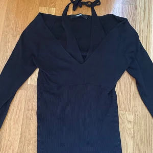 Svart ribbad långärmad tröja från Bikbok - Svart ribbad långärmad tröja från Bikbok med lång ärm och djup v-ringning. Tröjan har knytband i nacken, det är som ett linne under tröjan.