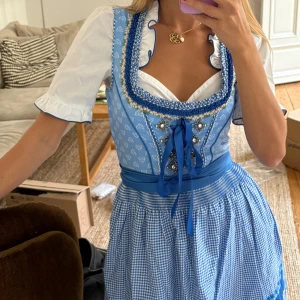 Blå och vit dirndlklänning med separat blus - Perfekt för oktoberfest! Dirndl storlek 34 men skulle säga att den passar xxs-s! Superfin blå och vit dirndlklänning med klassiskt rutigt förkläde, snörning framtill och dekorativa detaljer i blått och vitt. Märket på dirndl: AMISU