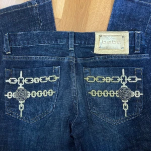 Bebe bootcut jeans med detaljer  - Mörkblå y2k flare/bootcut jeans från Bebe med broderier på fickorna. Passar XS/S (så mått i bilderna) 