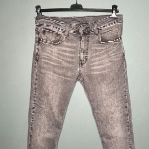 Levi's 512 grå jeans W32 L30 - Säljer ett par grå Levi's 512 jeans med snyggt tvättad look och klassiska fem fickor. Jeansen har smal passform och raka ben, tillverkade i mjukt jeanstyg. Perfekta för dig som gillar en stilren och modern vibe.