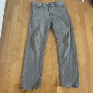 Grå straight fit jeans Jack & jones - Säljer ett par grå jeans från Jack & Jones med klassisk femficksdesign och rak passform. Jeansen har en snygg, neutral grå färg och är tillverkade i slitstarkt bomullsmaterial. Perfekt för dig som gillar enkel och stilren look.