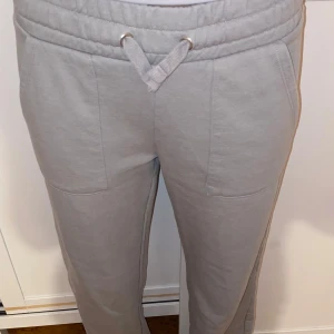 Grå och svarta mjukisbyxor med snörning - Två par mjukisbyxor, ett par ljusgrå och ett par mörkgrå/svarta. Båda har bred resår i midjan med snörning, stora fickor fram och bak samt raka ben. Perfekta för chill eller träning. Mjukt material som känns skönt mot huden. Från lager 157. 200 för båda. 